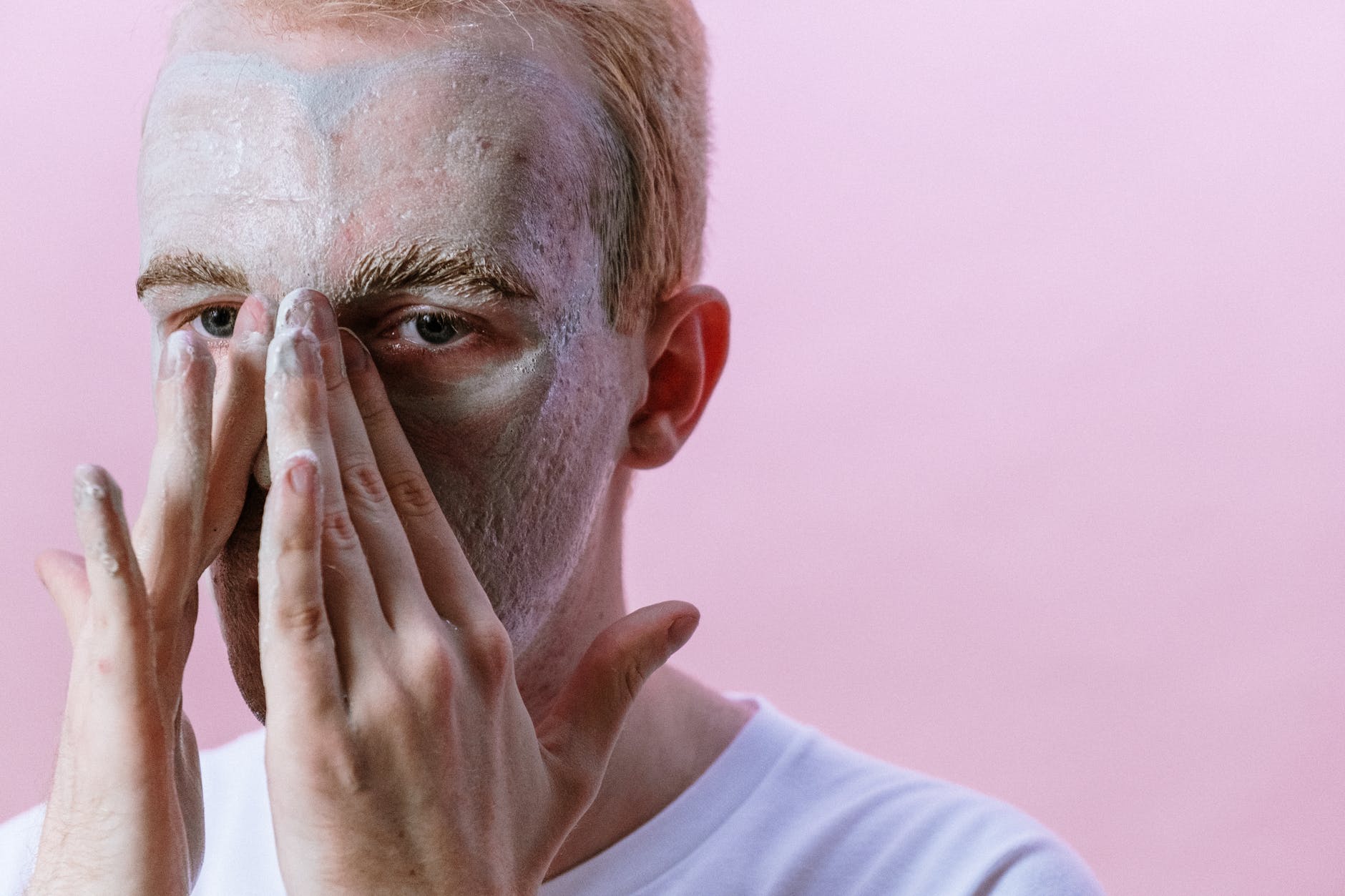 man in white crew neck shirt covering his face with his hand